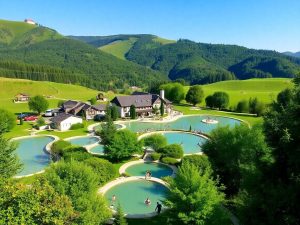 Peisaj balnear cu izvoare termale și oameni relaxându-se.